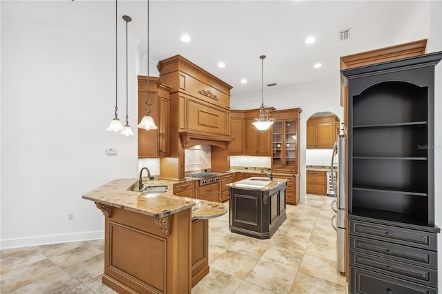 kitchen featuring visible vents, a sink, arched walkways, brown cabinetry, and stainless steel gas cooktop