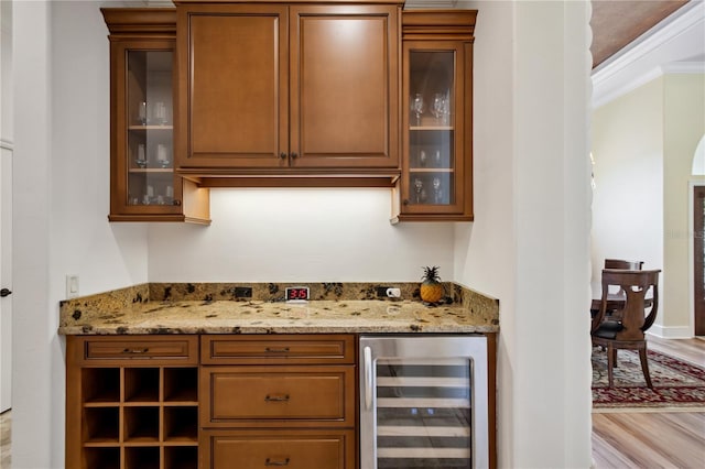 bar featuring a bar, wine cooler, wood finished floors, and ornamental molding