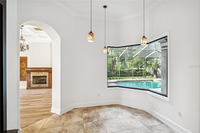 interior space with arched walkways, baseboards, a sunroom, and ornamental molding