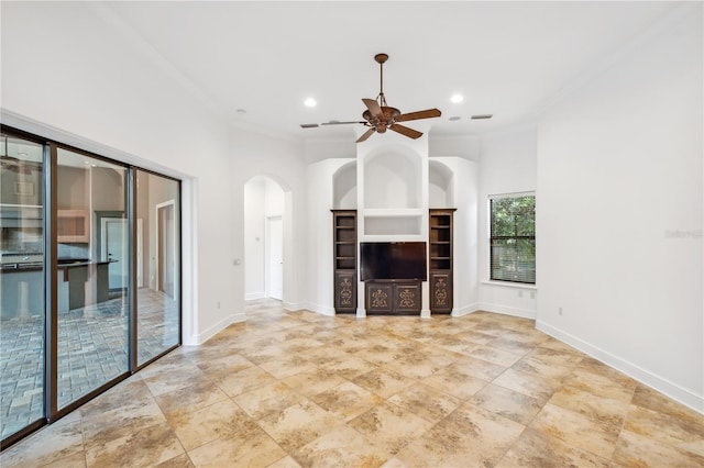 unfurnished living room featuring baseboards, arched walkways, and ornamental molding