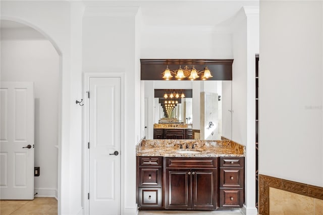 bathroom featuring a notable chandelier, ornamental molding, vanity, and tile patterned flooring