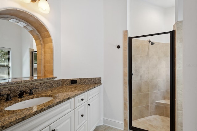 full bath with vanity, a shower stall, and baseboards