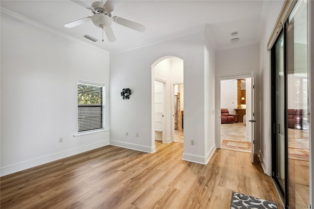 unfurnished bedroom with light wood finished floors, visible vents, baseboards, ornamental molding, and arched walkways