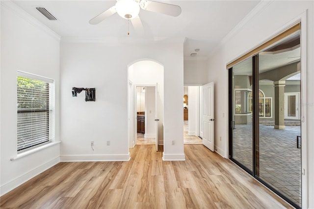 unfurnished bedroom with light wood-type flooring, visible vents, ornamental molding, a closet, and arched walkways