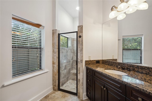 bathroom featuring a notable chandelier, baseboards, vanity, and a shower stall