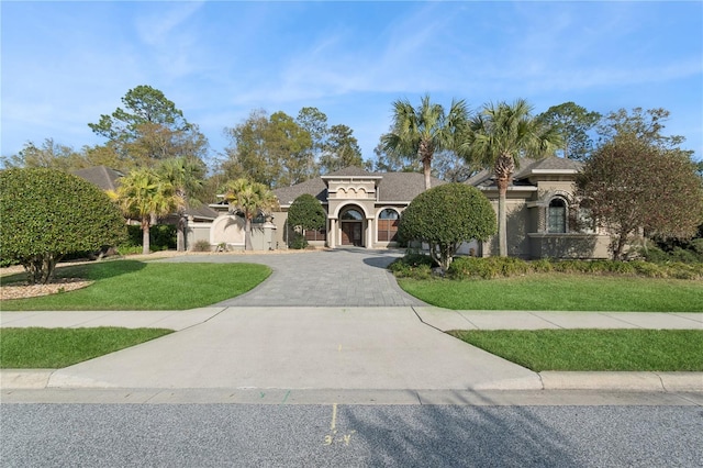 mediterranean / spanish house with stucco siding, curved driveway, and a front lawn