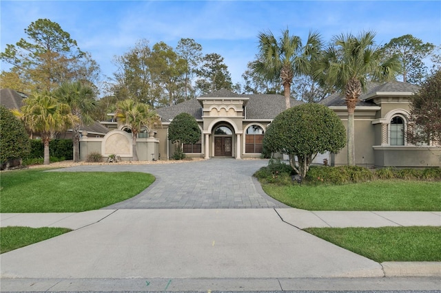 mediterranean / spanish-style home with decorative driveway, a front lawn, and stucco siding