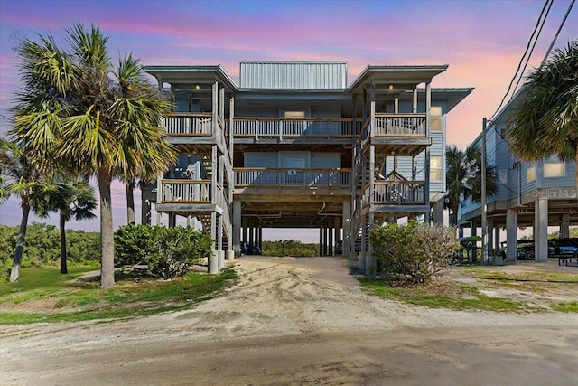 view of building exterior with dirt driveway, a carport, and stairs