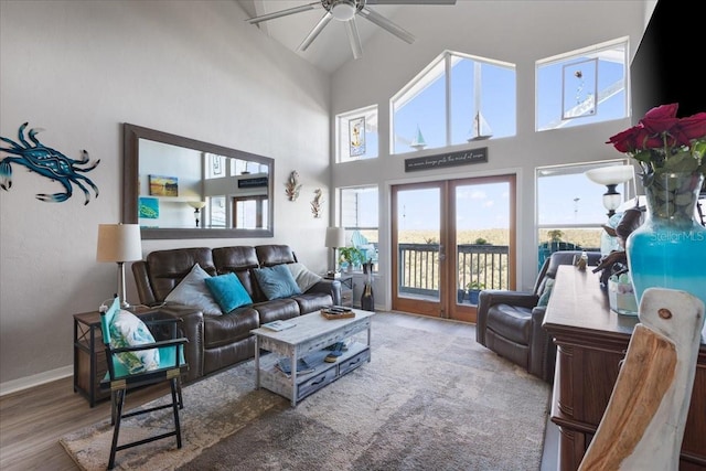 living room with a towering ceiling, baseboards, a ceiling fan, and french doors