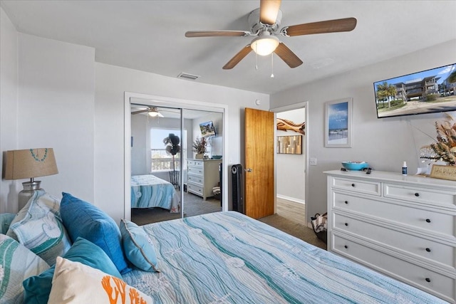 bedroom featuring baseboards, visible vents, a ceiling fan, dark colored carpet, and a closet