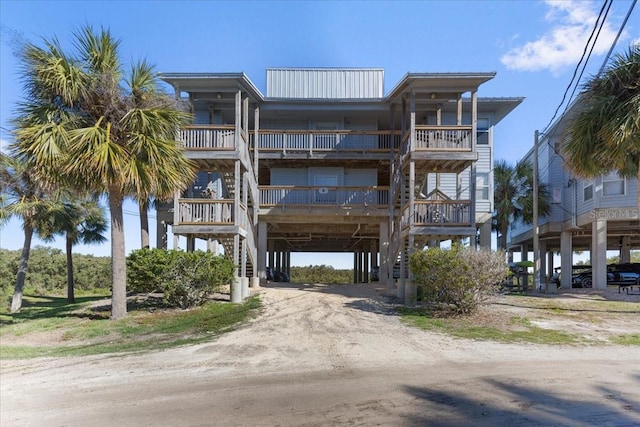 view of property with dirt driveway, a carport, and stairway