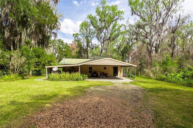 rear view of house with an attached carport, a yard, and dirt driveway