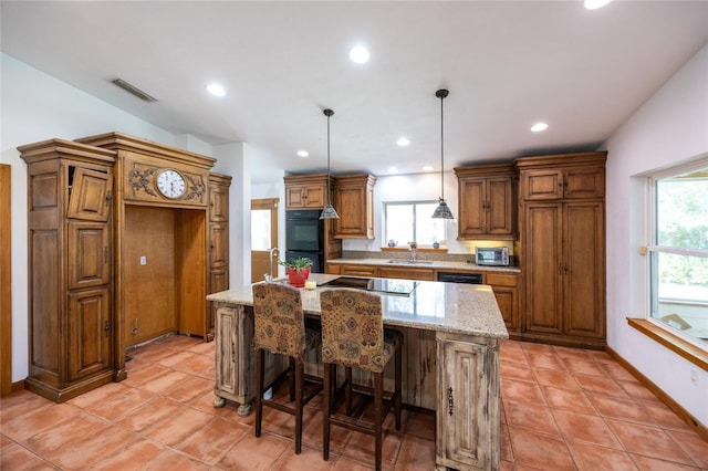 kitchen featuring visible vents, black appliances, a center island with sink, decorative light fixtures, and brown cabinetry