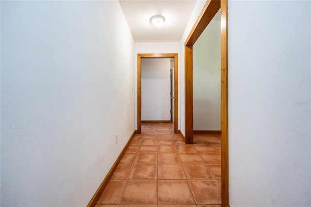 hallway with light tile patterned floors and baseboards