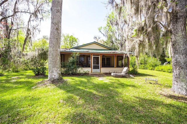 back of property featuring a lawn, a sunroom, and metal roof