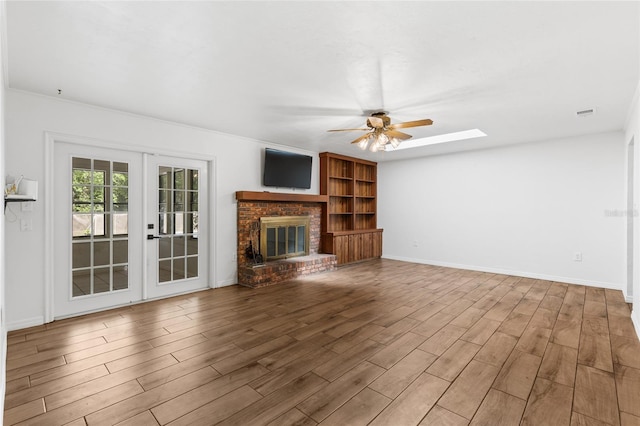 4031 NW 75th St, Gainesville, FL 32606 - unfurnished living room featuring baseboards, a fireplace, wood finished floors, a ceiling fan, and french doors