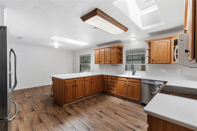 4031 NW 75th St, Gainesville, FL 32606 - kitchen with a sink, open shelves, a skylight, a peninsula, and stainless steel appliances