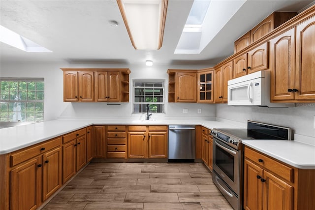 4031 NW 75th St, Gainesville, FL 32606 - kitchen with a skylight, appliances with stainless steel finishes, a sink, open shelves, and brown cabinetry