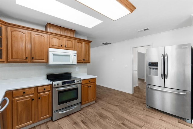 4031 NW 75th St, Gainesville, FL 32606 - kitchen with light wood-style flooring, stainless steel appliances, brown cabinetry, and visible vents