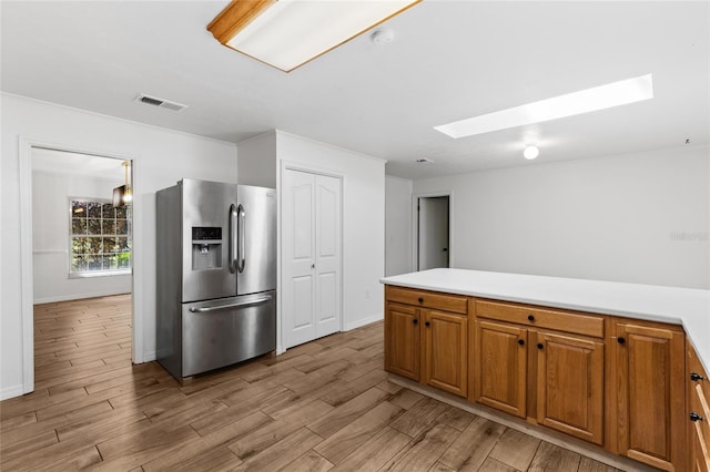4031 NW 75th St, Gainesville, FL 32606 - kitchen featuring stainless steel fridge with ice dispenser, a skylight, light wood-style floors, visible vents, and brown cabinets