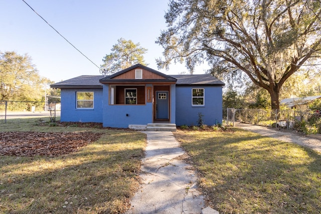 bungalow-style home featuring a front yard, fence, and stucco siding