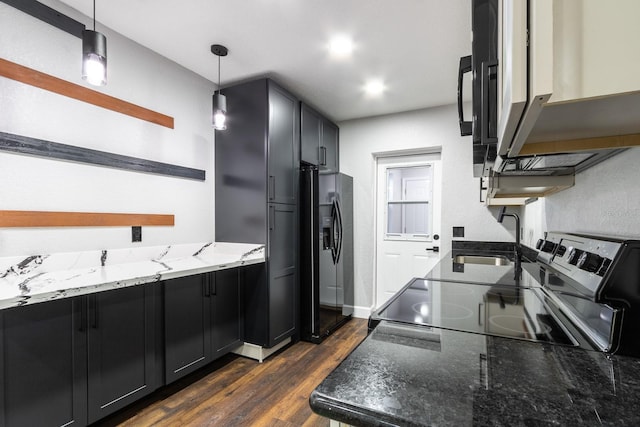 kitchen with stone counters, dark cabinets, a sink, hanging light fixtures, and black refrigerator with ice dispenser