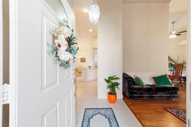 foyer with a ceiling fan, baseboards, and light tile patterned floors