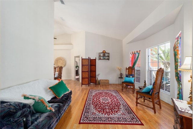 sitting room featuring lofted ceiling, baseboards, and light wood-style floors