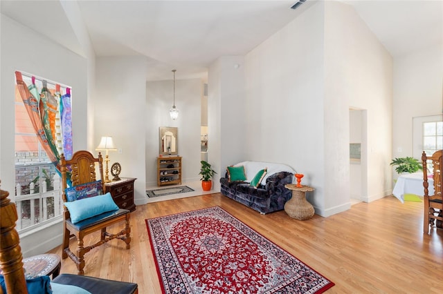 sitting room with high vaulted ceiling, visible vents, baseboards, and wood finished floors