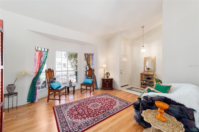 living area featuring baseboards, vaulted ceiling, and wood finished floors