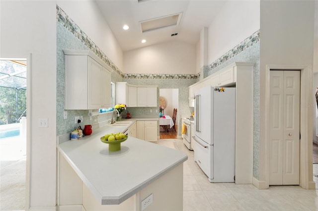 kitchen with light tile patterned floors, light countertops, a sink, white appliances, and a peninsula