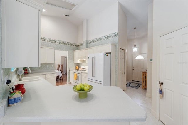 kitchen featuring white appliances, a peninsula, light countertops, high vaulted ceiling, and a sink