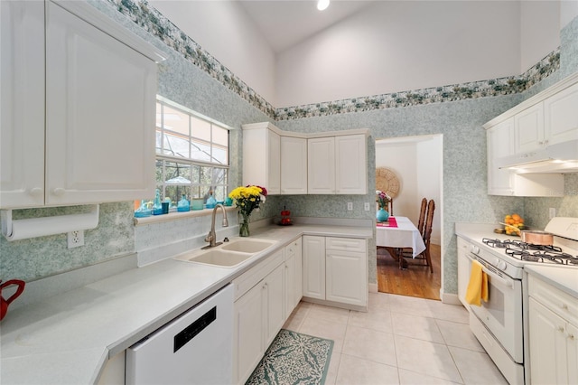 kitchen featuring light tile patterned floors, under cabinet range hood, white appliances, a sink, and light countertops