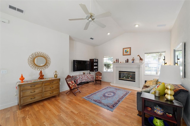 living room featuring lofted ceiling, visible vents, a tiled fireplace, and wood finished floors