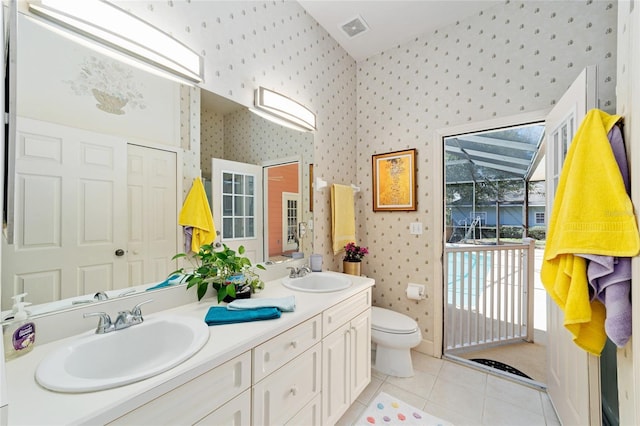 bathroom featuring a sink, toilet, and wallpapered walls