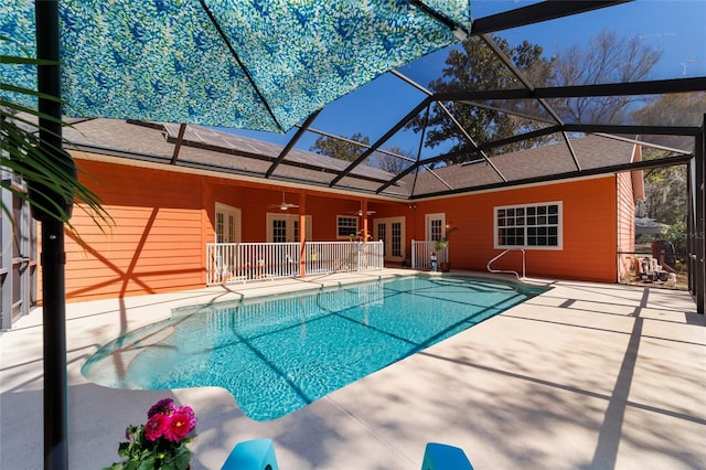 outdoor pool with a ceiling fan, glass enclosure, a patio area, and french doors