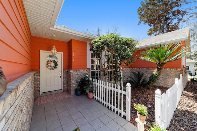 doorway to property featuring fence and brick siding