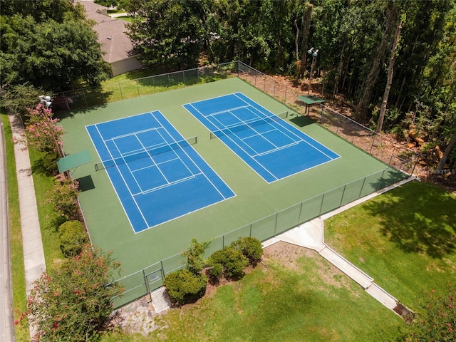 view of tennis court featuring fence and a lawn