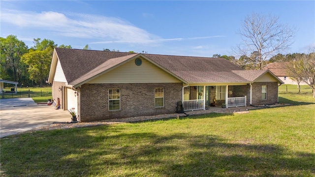 view of front of home with a garage, concrete driveway, covered porch, a front lawn, and brick siding