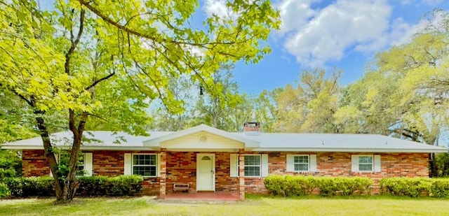 ranch-style house with a chimney, a front lawn, and brick siding