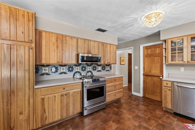 kitchen with visible vents, glass insert cabinets, stainless steel appliances, and light countertops