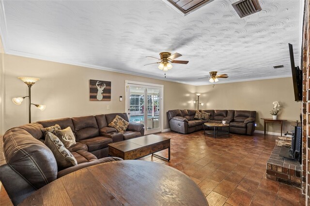 living room with a textured ceiling, baseboards, visible vents, and crown molding