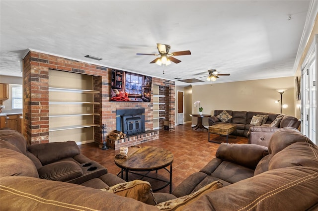 living room featuring a textured ceiling, visible vents, built in features, a wood stove, and crown molding