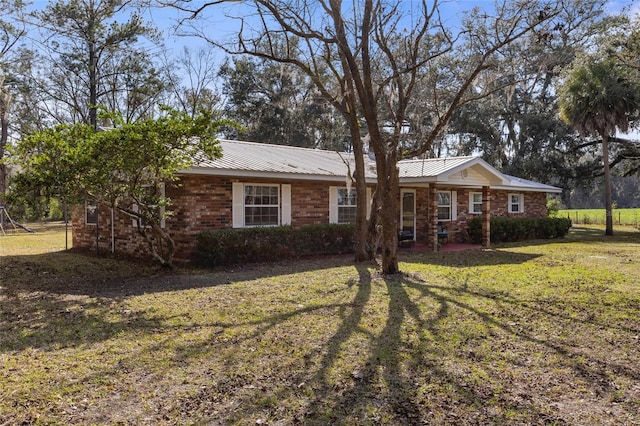 ranch-style home with metal roof, a front lawn, and brick siding