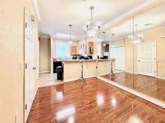 kitchen featuring a breakfast bar, light wood-style floors, ornamental molding, a chandelier, and a peninsula