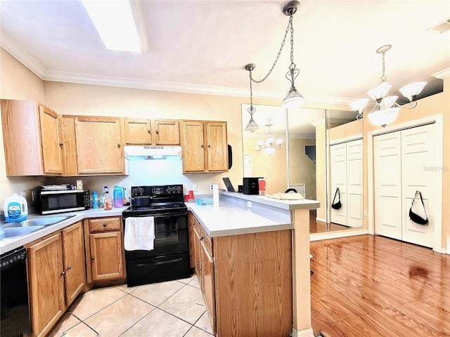 kitchen featuring pendant lighting, light countertops, a chandelier, under cabinet range hood, and black appliances