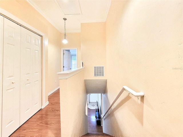 staircase with baseboards, crown molding, visible vents, and wood finished floors