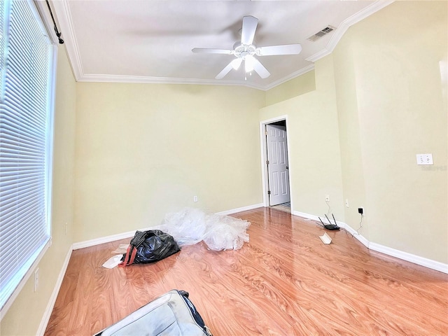 spare room with light wood finished floors, baseboards, visible vents, and ornamental molding