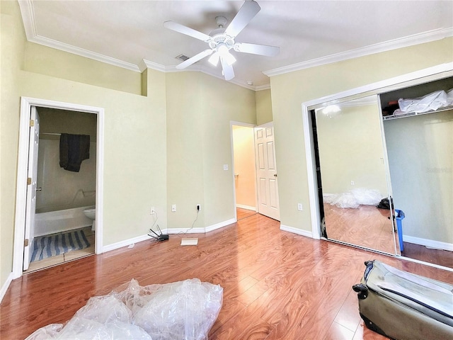 bedroom featuring light wood finished floors, visible vents, baseboards, crown molding, and a closet