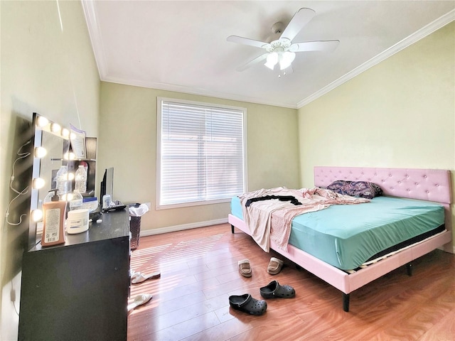 bedroom with baseboards, ornamental molding, ceiling fan, and wood finished floors